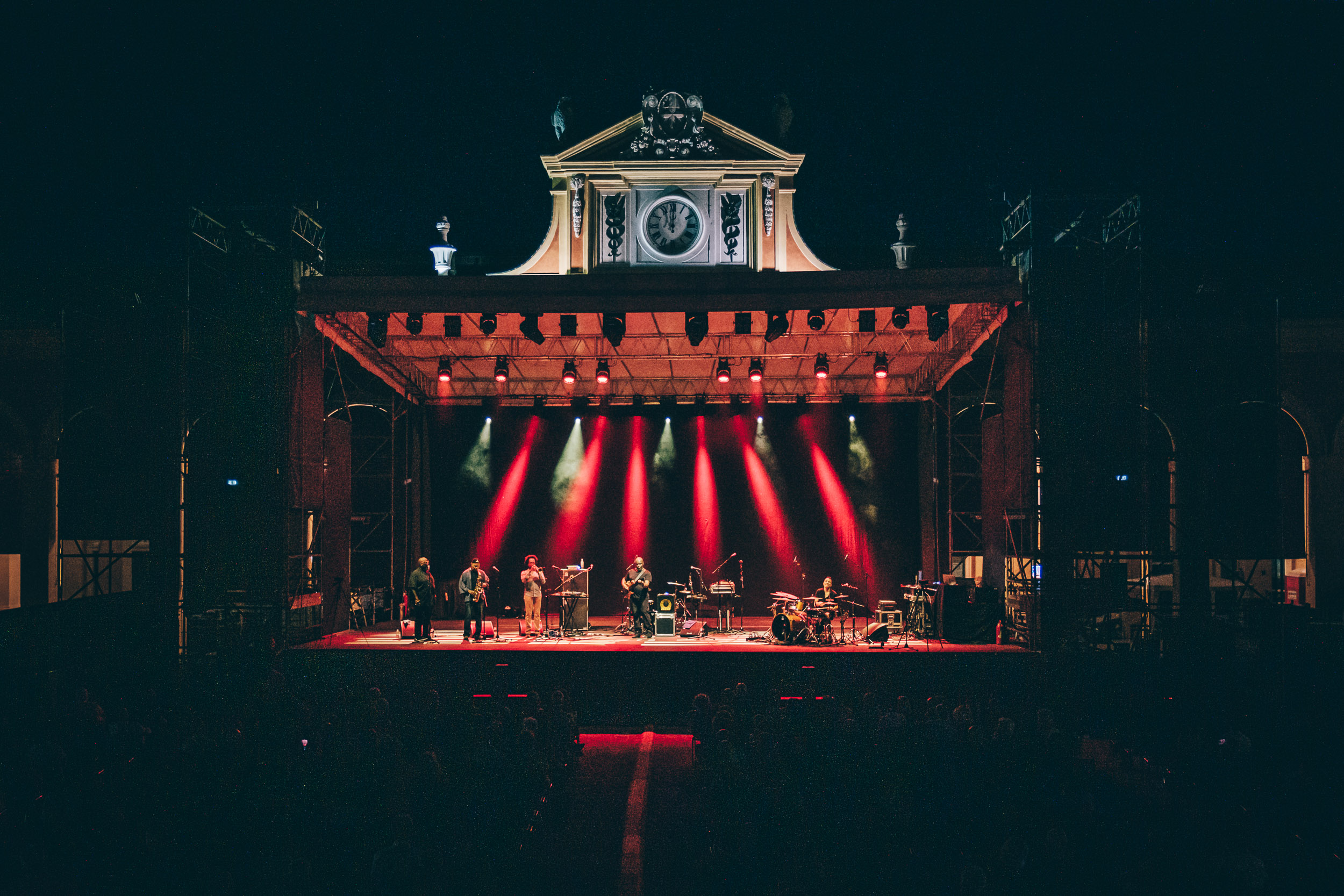 Wide view of an outdoor concert under red stage lights