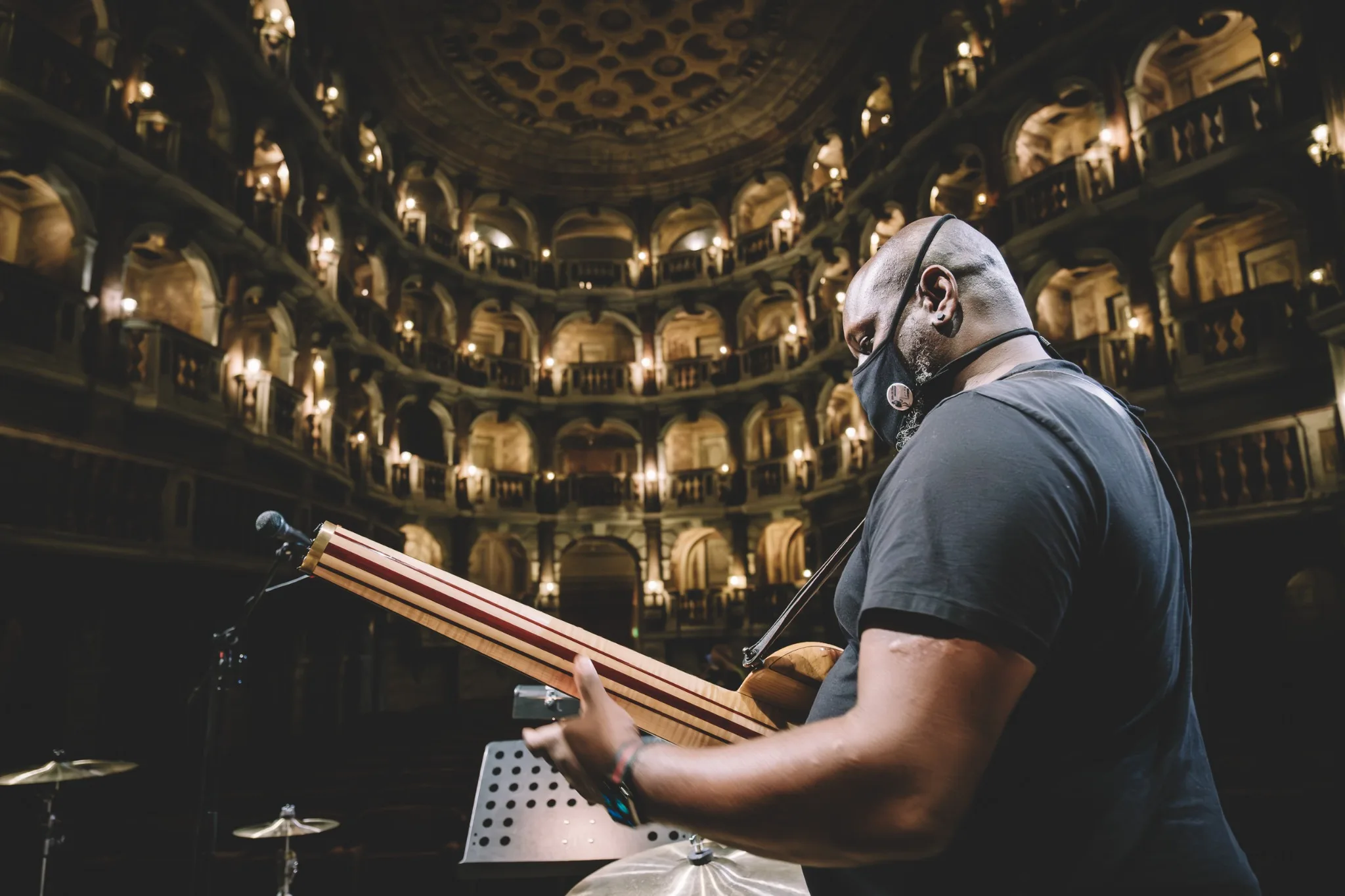 Anthony Tidd holding an electric bass in an ornate theatre.