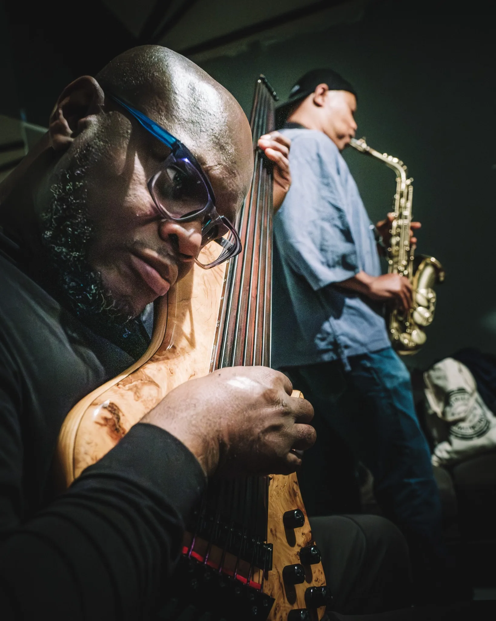 Anthony Tidd in the foreground with Steve Coleman holding a saxophone behind him backstage.