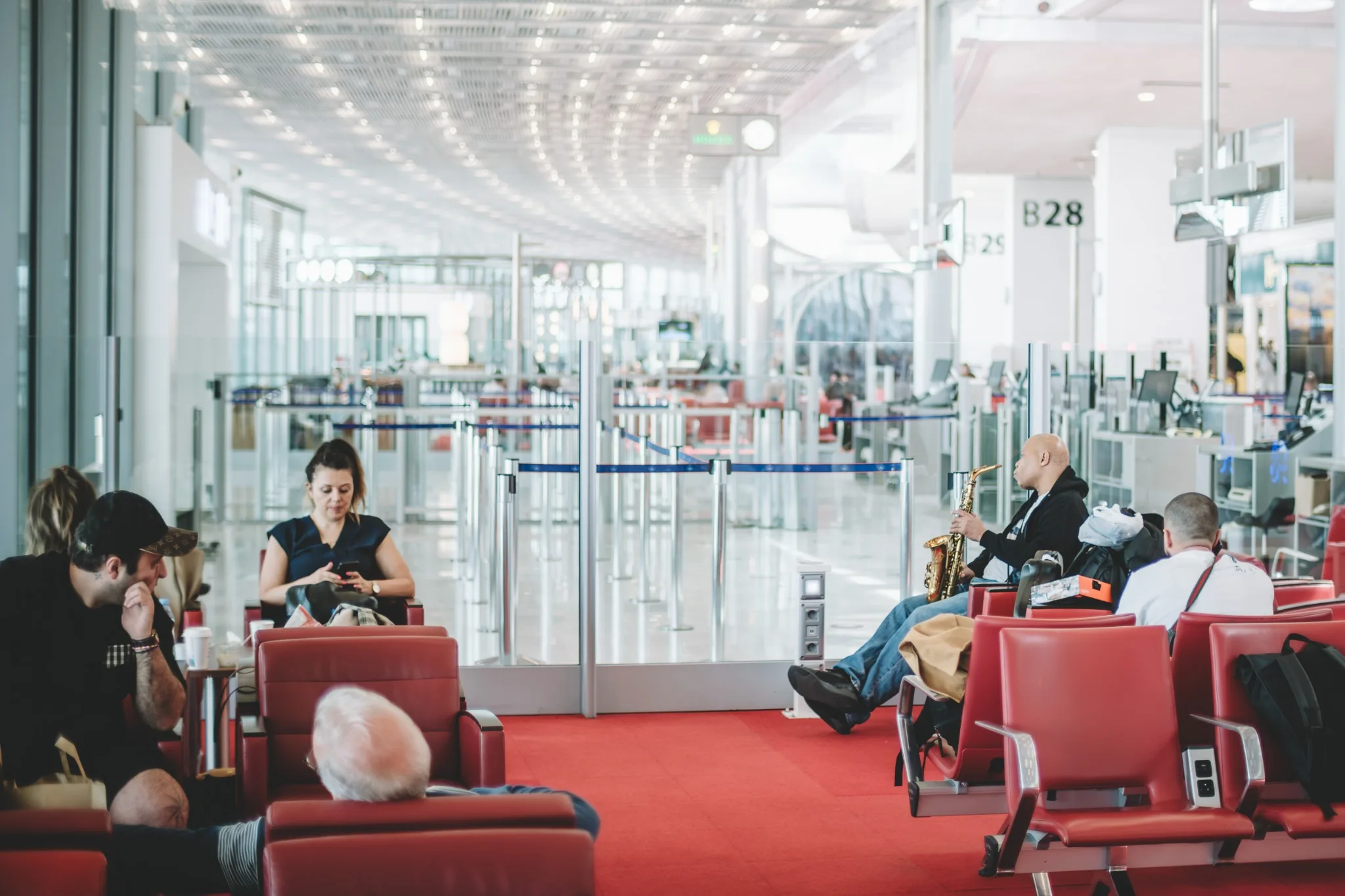 Steve Coleman seated in an airport waiting area beside red chairs.