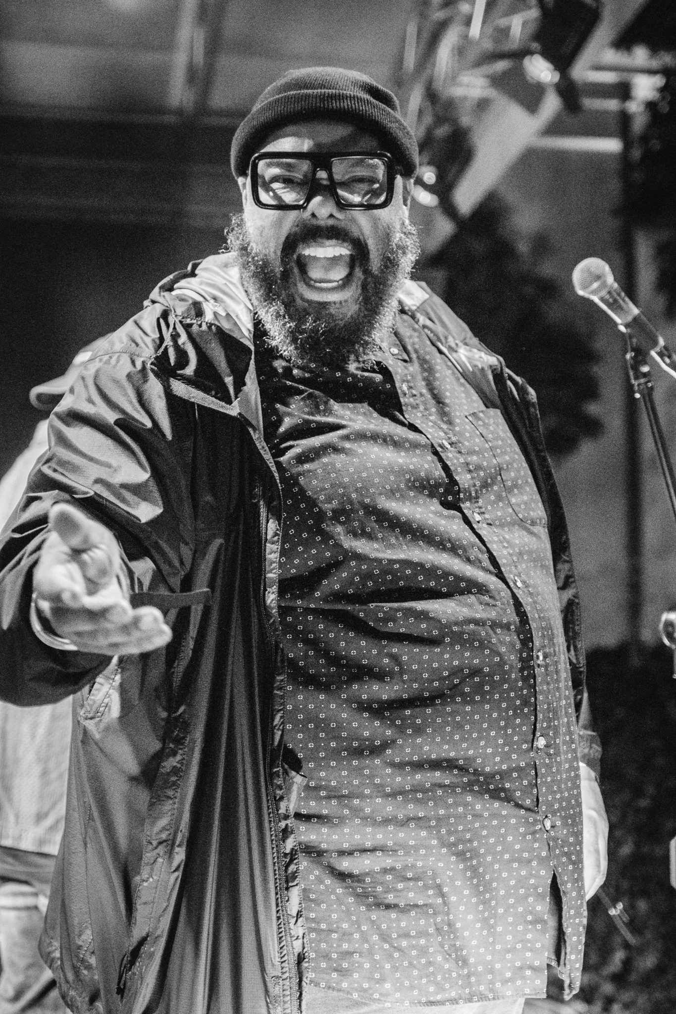 Black-and-white portrait of Kokayi smiling beside a microphone.