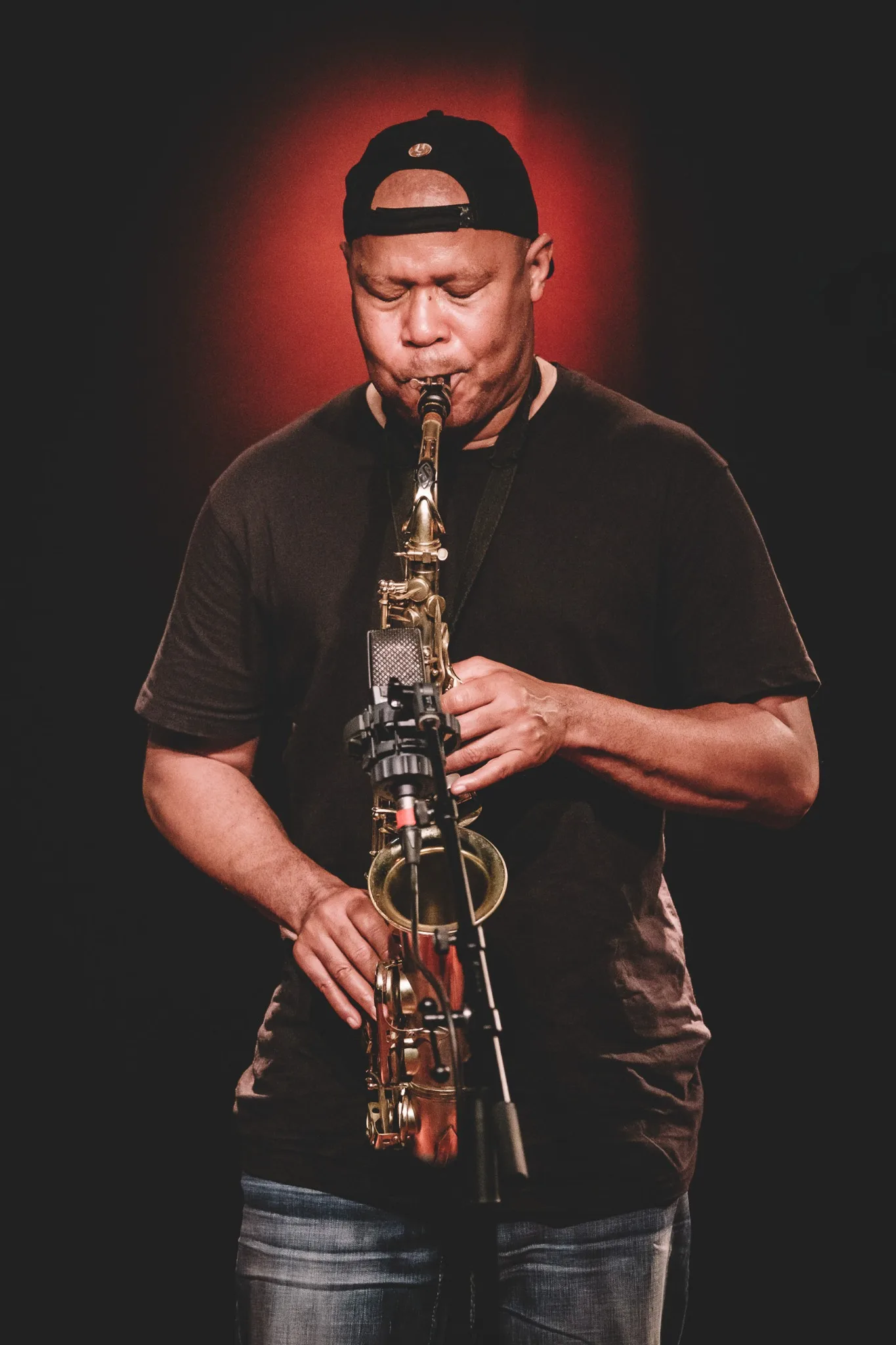 Steve Coleman playing alto saxophone against a dark background.