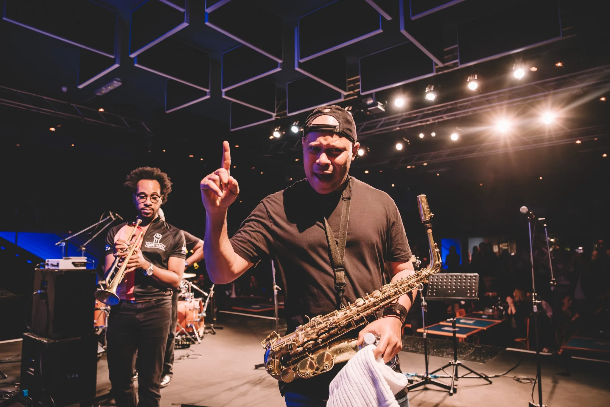 Steve Coleman holding his saxophone and raising one finger on stage at Blue Note Milano.