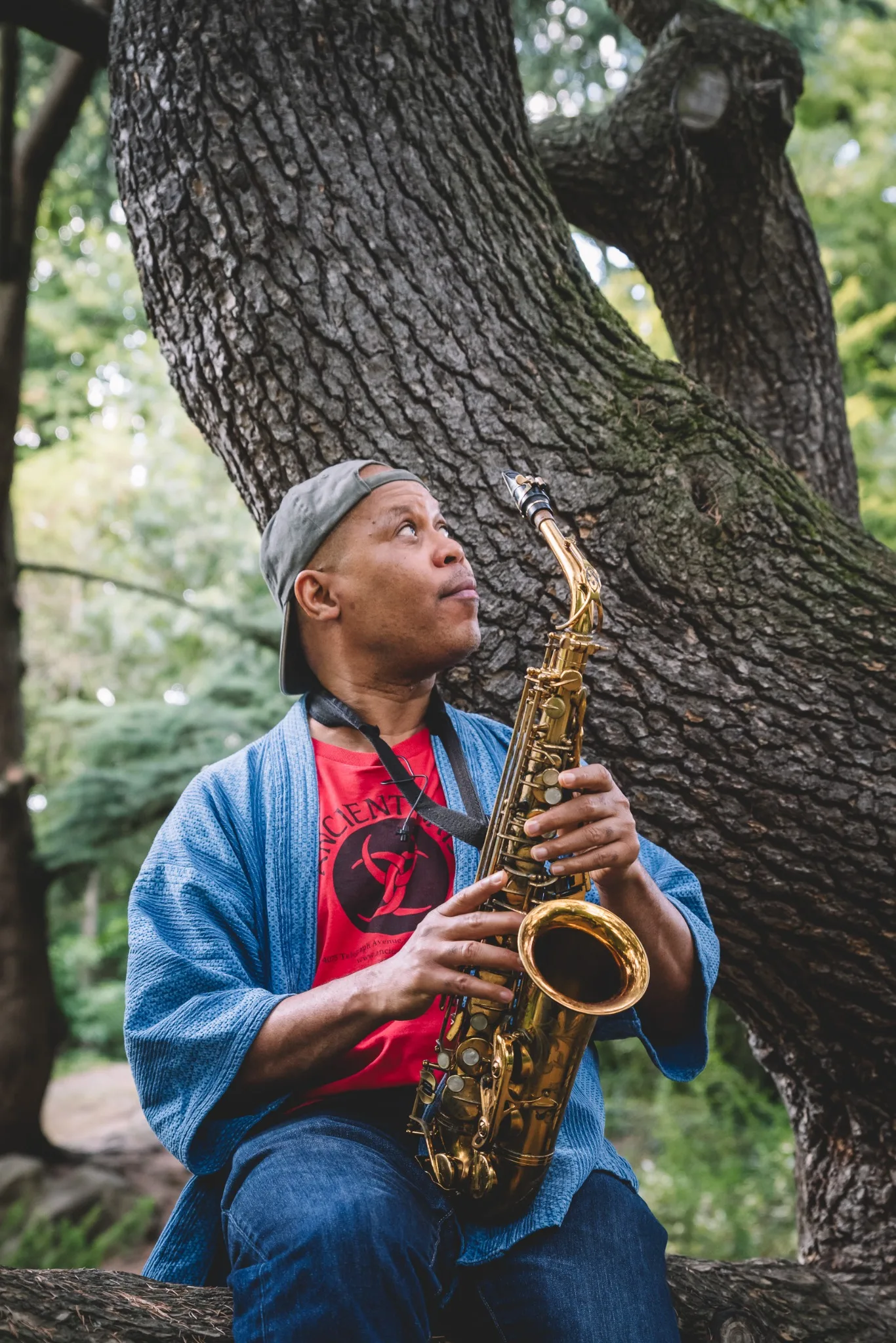 Steve Coleman playing alto saxophone beneath a tree.