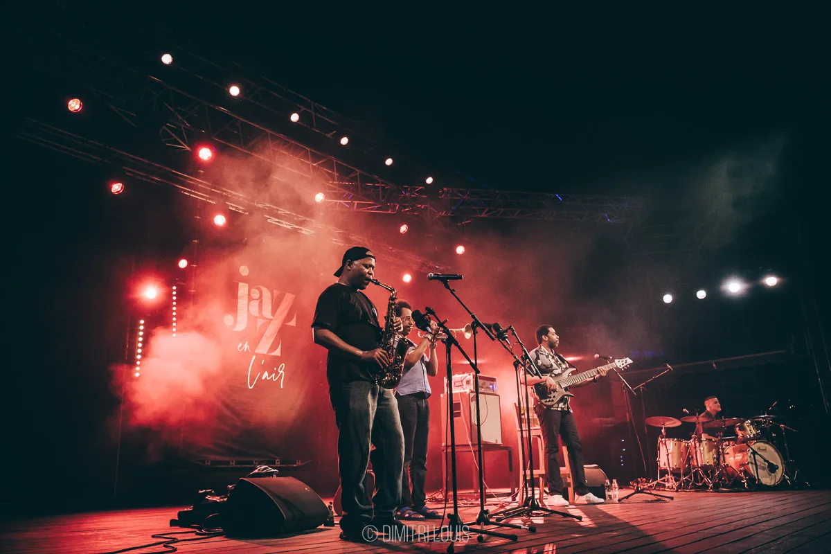 Five Elements on stage beneath red lighting, viewed from the audience.