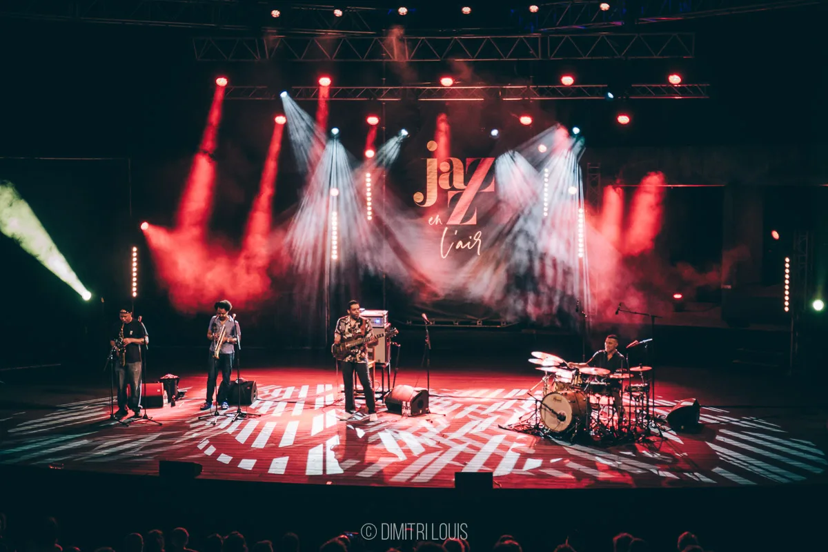 Wide view of Five Elements performing beneath red and white lights at Jazz en l’Air.