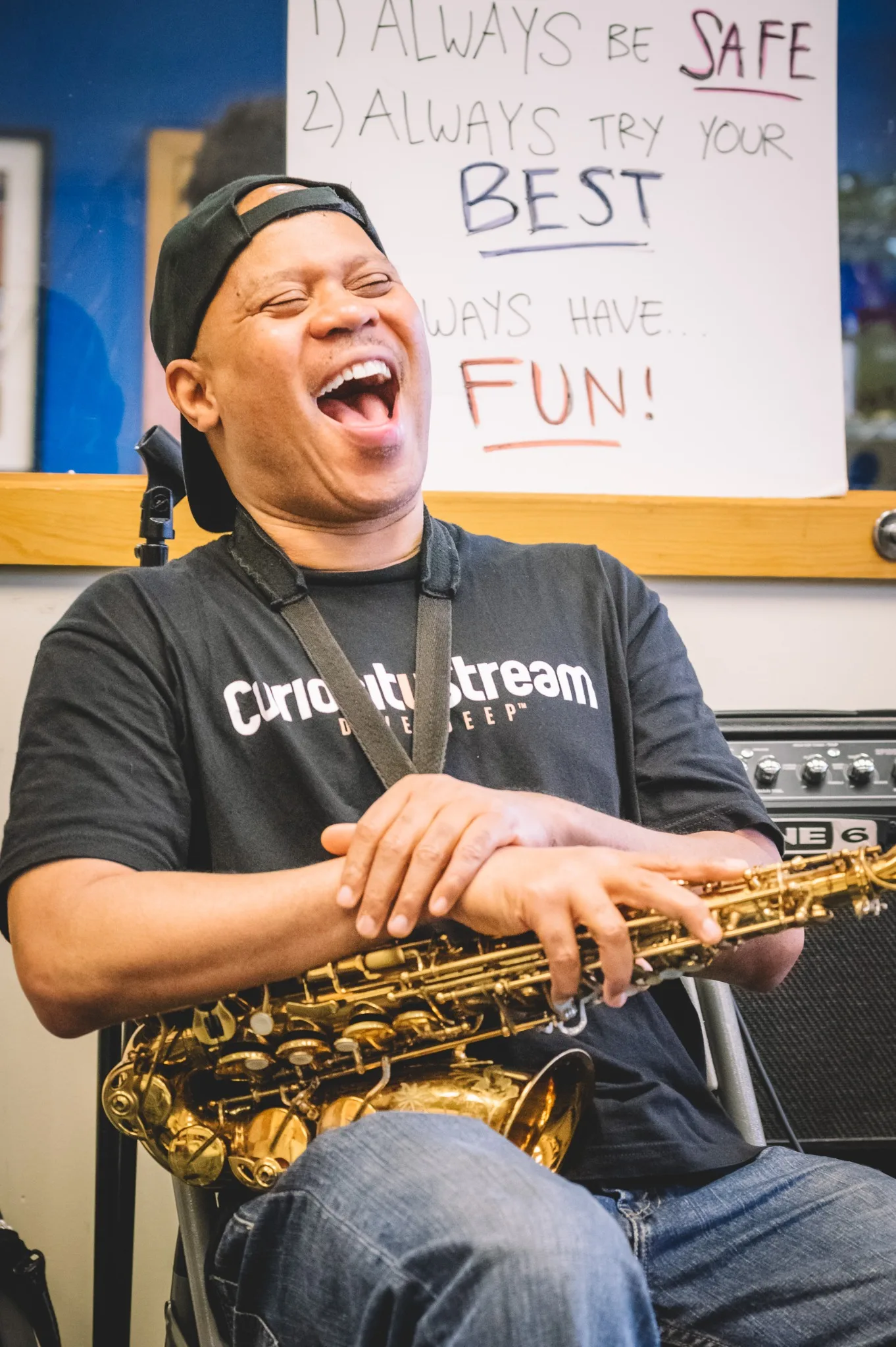 Steve Coleman laughing with a saxophone resting across his lap.